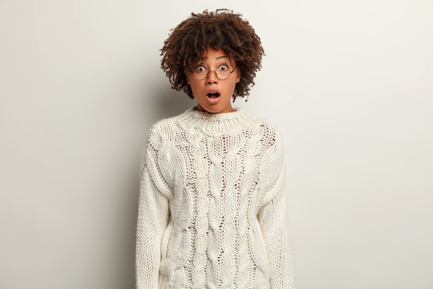 Jeune femme avec coupe de cheveux afro portant un pull blanc