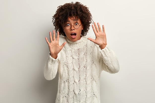 Jeune femme avec coupe de cheveux afro portant un pull blanc