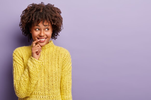 Jeune femme avec coupe de cheveux afro portant un pull jaune