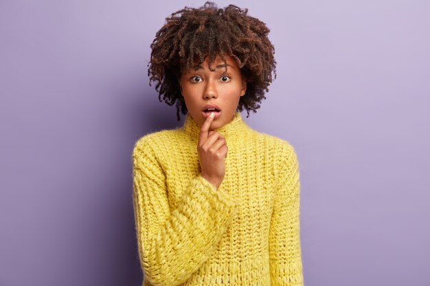 Jeune femme avec coupe de cheveux afro portant un pull jaune