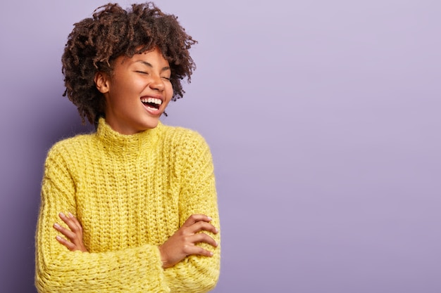 Jeune femme avec coupe de cheveux afro portant un pull jaune