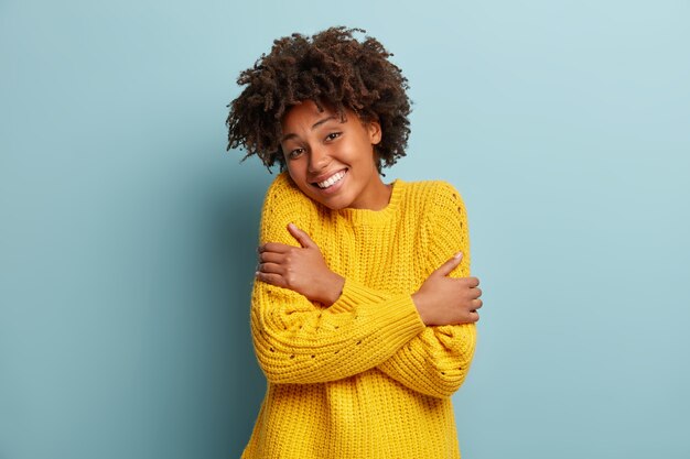Jeune femme avec coupe de cheveux afro portant un pull jaune