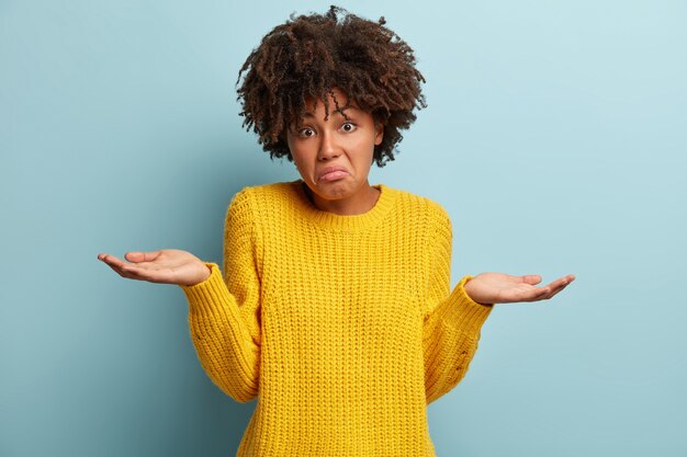 Une jeune femme avec une coupe de cheveux afro portant un pull jaune