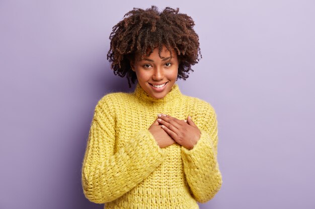 Jeune femme avec coupe de cheveux afro portant un pull jaune