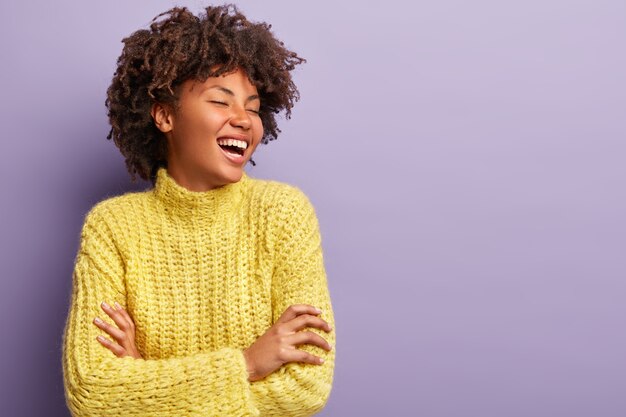 Jeune femme avec coupe de cheveux afro portant un pull jaune