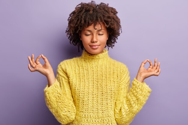 Jeune femme avec coupe de cheveux afro portant un pull jaune