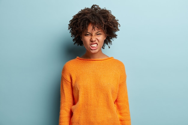 Jeune femme avec coupe de cheveux afro portant un pull orange