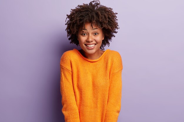 Jeune femme avec coupe de cheveux afro portant un pull orange