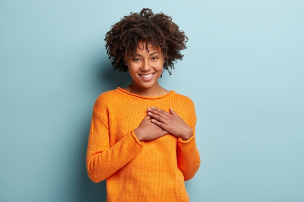 Jeune femme avec coupe de cheveux afro portant un pull orange