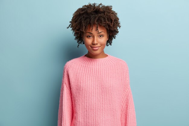 Jeune femme avec coupe de cheveux afro portant un pull rose