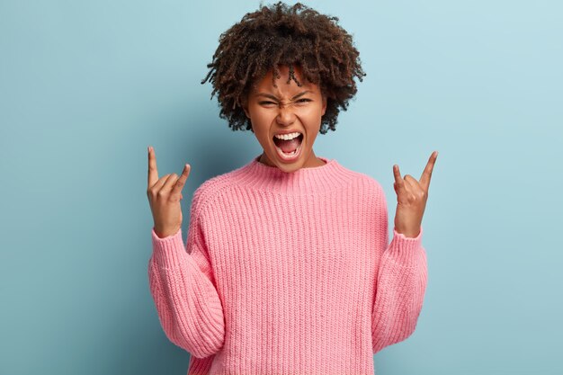 Jeune femme avec coupe de cheveux afro portant un pull rose