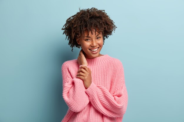 Jeune femme avec coupe de cheveux afro portant un pull rose