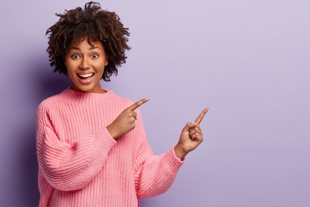 Jeune femme avec coupe de cheveux afro portant un pull rose