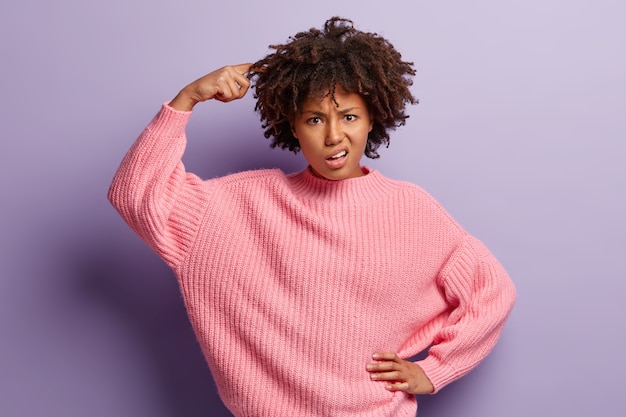 Jeune femme avec coupe de cheveux afro portant un pull rose