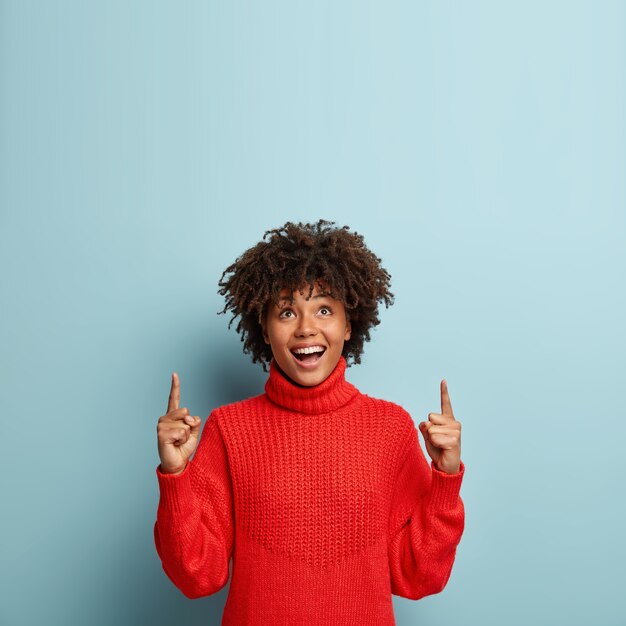 Jeune femme avec coupe de cheveux afro portant un pull rouge