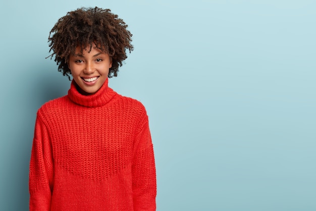 Jeune femme avec coupe de cheveux afro portant un pull rouge