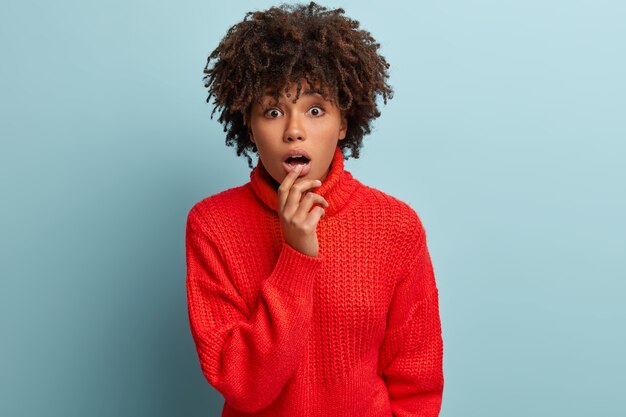 Jeune femme avec coupe de cheveux afro portant un pull rouge