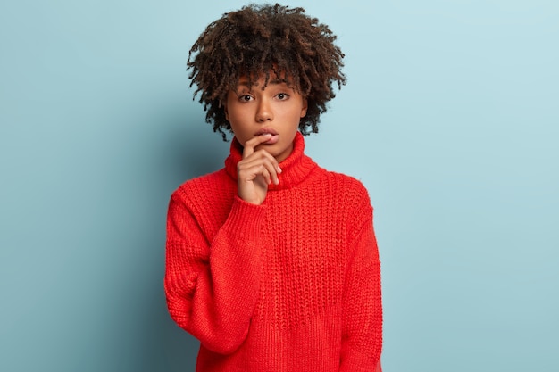 Jeune femme avec coupe de cheveux afro portant un pull rouge