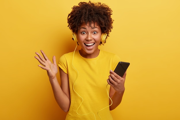 Jeune femme avec coupe de cheveux afro, t-shirt jaune et écouteurs