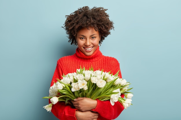 Photo gratuite jeune femme avec coupe de cheveux afro tenant un bouquet de fleurs blanches