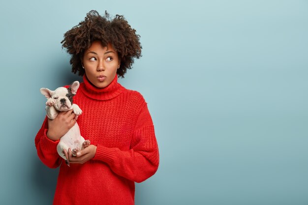 Jeune femme avec coupe de cheveux afro tenant petit chien