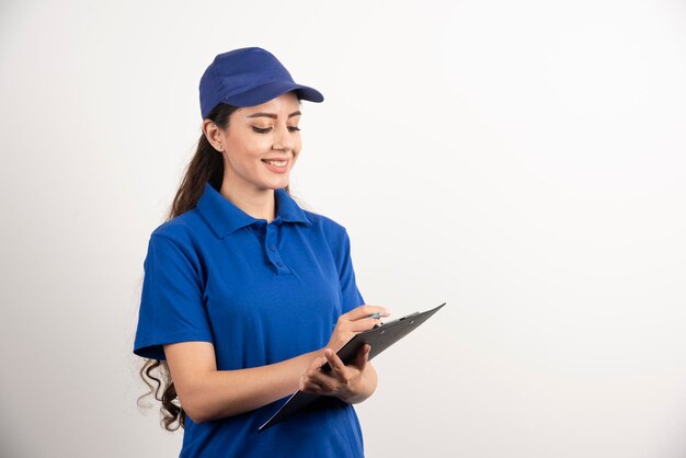 Jeune femme coursier en gommages bleus tenant un presse-papiers. photo de haute qualité