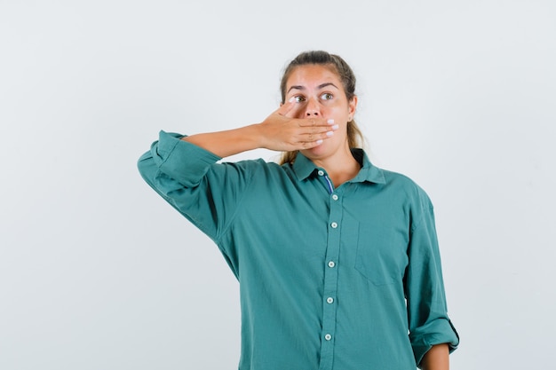 Photo gratuite jeune femme couvrant la bouche avec la main en chemisier vert et à la surprise