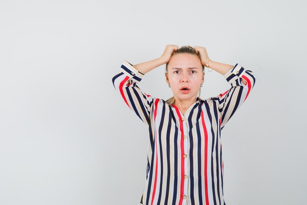 Jeune femme couvrant sa tête avec les mains en chemisier rayé et à choqué