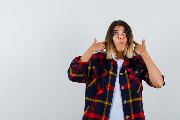 Jeune femme couvrant ses oreilles avec les doigts sur fond blanc