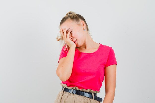 Jeune femme couvrant le visage avec la main en t-shirt et pantalon et à la superbe