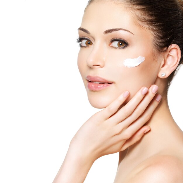 Jeune femme avec de la crème cosmétique sur un visage frais et propre. Concept de soins de la peau