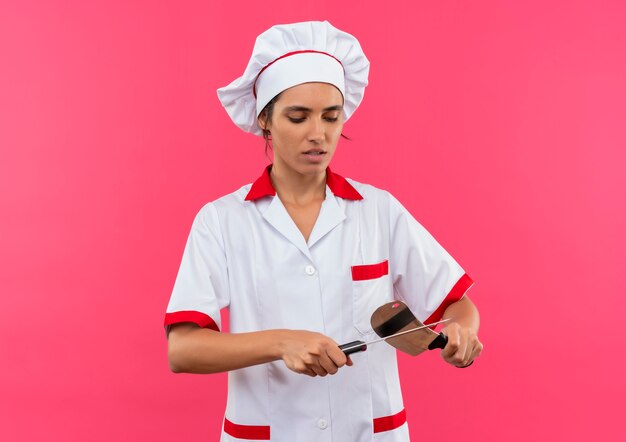 Jeune femme cuisinière portant un couteau sharpes uniforme de chef avec couperet avec copie espace