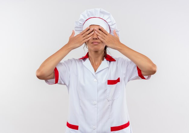 Jeune femme cuisinière portant l'uniforme de chef couvert les yeux avec la main avec copie espace