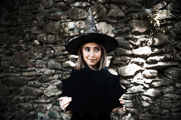 Photo gratuite jeune femme, dans, chapeau sorcière, tenue, décoration halloween, et, regarder loin