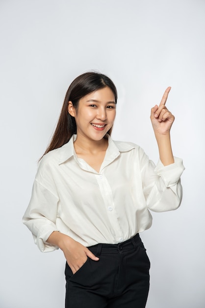 Une jeune femme dans une chemise blanche et pointant vers le haut