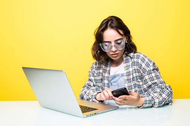 Jeune femme, dans, lunettes soleil, séance, textos, à, elle, bureau, sur, elle, téléphone portable, à, ordinateur portable, devant