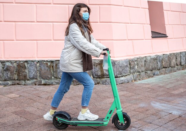 Jeune femme dans un masque médical sur un scooter électrique