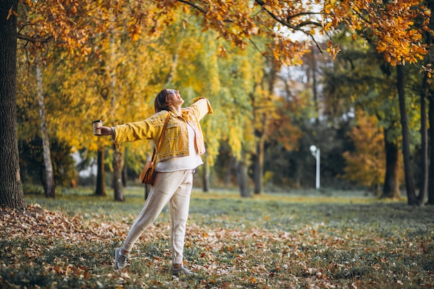Jeune femme dans un parc en automne, boire du café