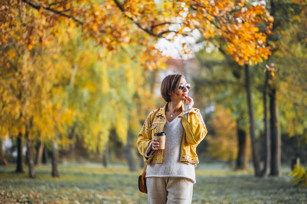 Jeune femme dans un parc en automne, boire du café