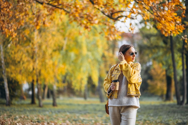 Jeune femme dans un parc en automne, boire du café