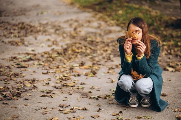 Photo gratuite jeune femme dans le parc, fermant les yeux avec des feuilles d'automne