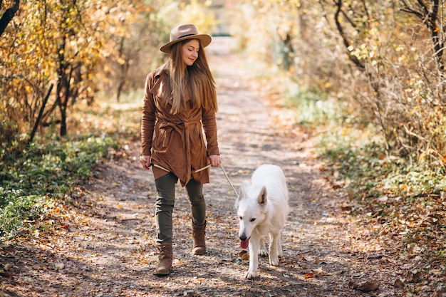 Jeune femme dans un parc avec son chien blanc