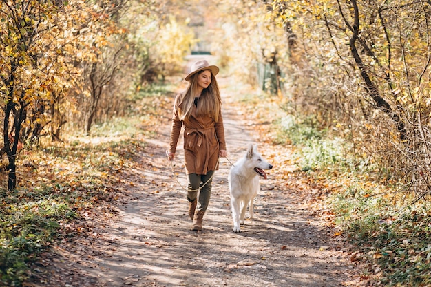 Jeune femme dans un parc avec son chien blanc