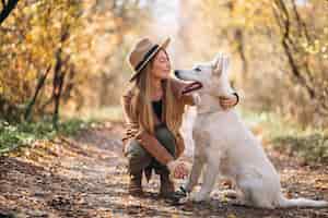Photo gratuite jeune femme dans un parc avec son chien blanc