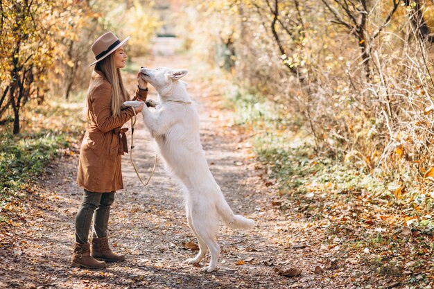 Jeune femme dans un parc avec son chien blanc