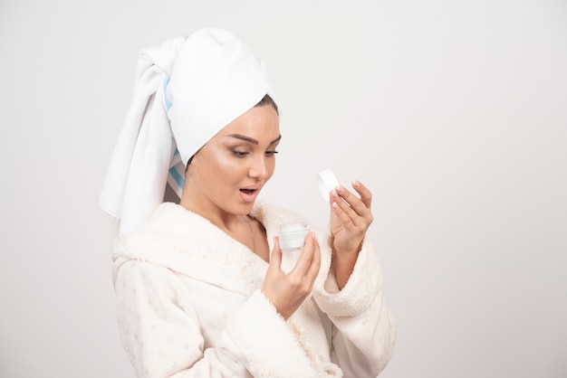 Jeune femme dans un peignoir appliquant une crème.