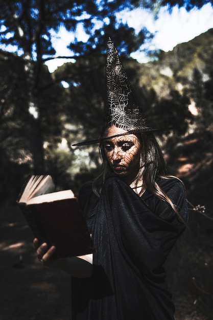 Jeune femme, dans, sorcier, costume, lecture, livre, dans, forêt