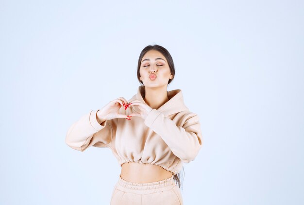 Jeune femme dans un sweat à capuche rose donnant des poses charmantes et chaleureuses