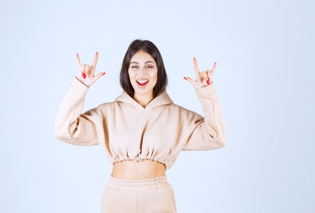 Jeune femme dans un sweat à capuche rose faisant signe d'oreille de loup