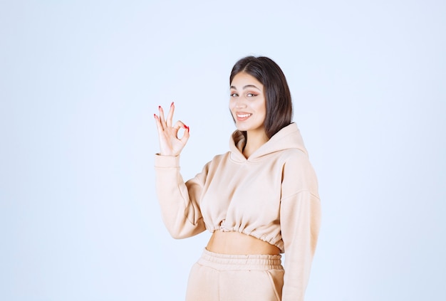 Jeune femme dans un sweat à capuche rose montrant un bon signe de la main